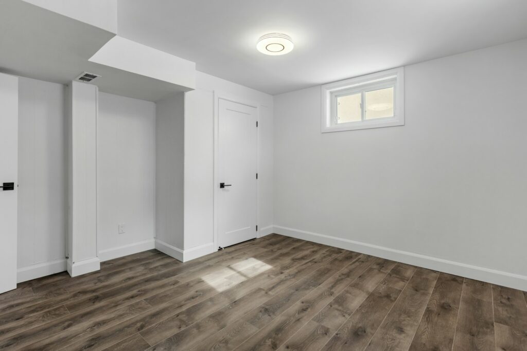 Finished basement with white walls and a wood-look plank floor